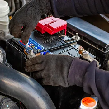 Person fixing car battery under hood