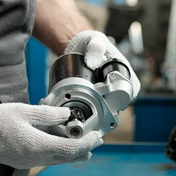 Person examining motor part in workshop.